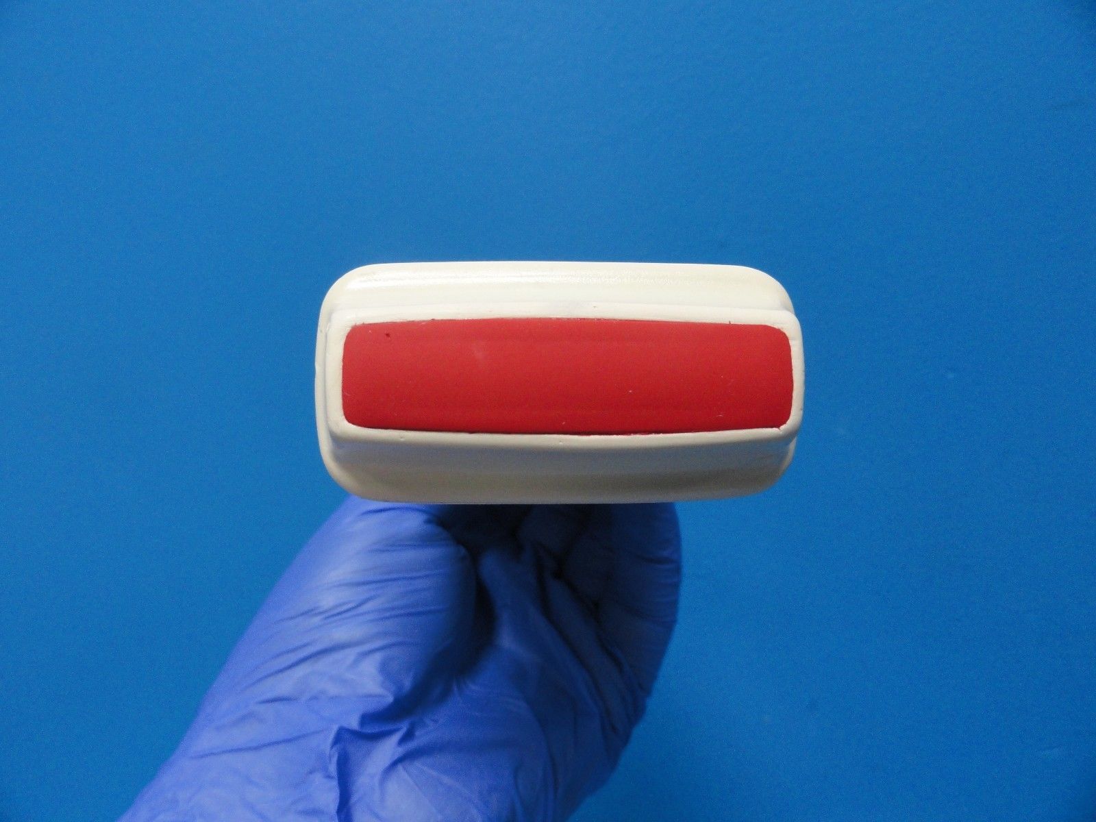 a blue gloved hand holding a red probe head lense