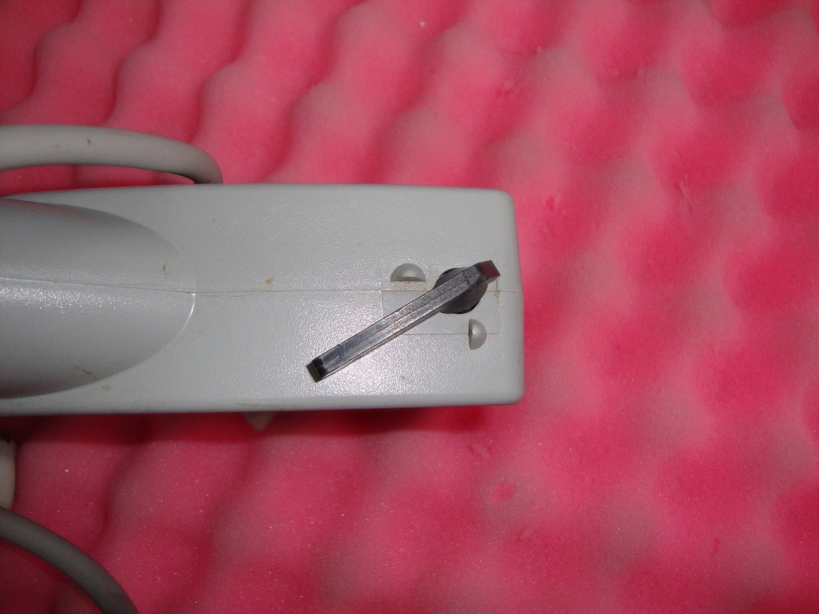 a white electrical device with a small piece of wire sticking out of it