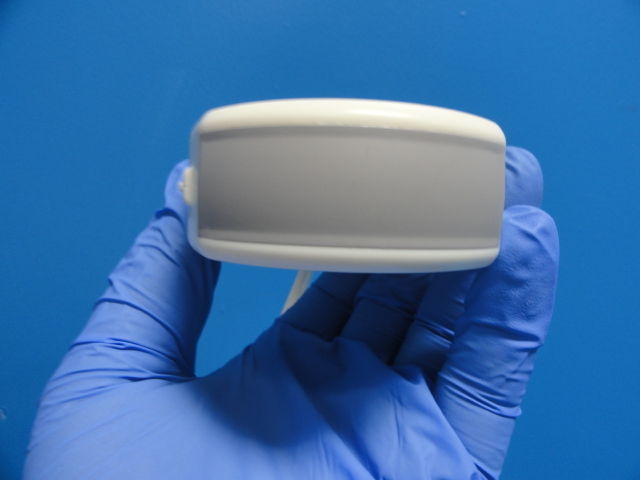 a gloved hand holding a white object in front of a blue background